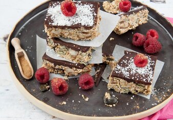 Auf dem Foto sind Brownies mit Schokoglasur zu sehen. Diese liegen schön angerichtet mit Himbeeren auf einem schwarzen Teller. | © SONNENTOR