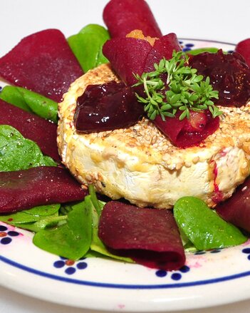 Auf dem Foto ist gebackener Camembert auf roten Rüben zu sehen. Garniert ist der Camembert mit Sauerkresse. | © SONNENTOR