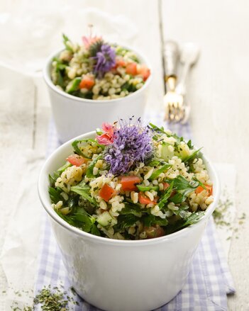 Auf dem Foto sind zwei Schälchen mit buntem Bulgursalat mit lila Blüten zu sehen. | © SONNENTOR