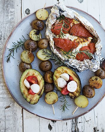 Auf dem Foto sieht man einen Teller mit allerlei vegetarischem Grillgut. Beispielsweise sieht man Kartoffelspieße, Avocados und ein Tomaten-Feta Päckchen. | © SONNENTOR