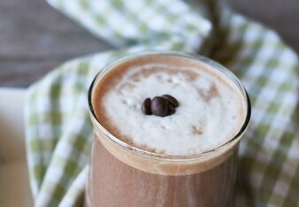 Auf dem Foto sieht man ein Glas mit Kaffee-Schoko-Chili-Smoothie. Das Glas steht auf einem grün-weiß kariertem Tuch. | © SONNENTOR