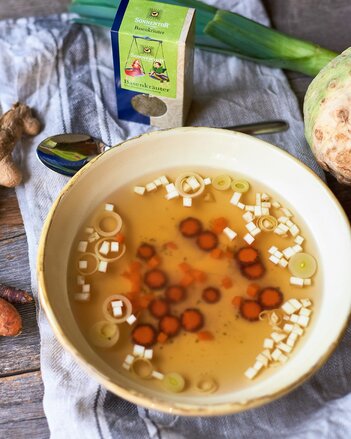 Auf dem Foto ist ein Teller mit Basensuppe und Suppengemüse zu sehen. Dahinter steht eine Packung Basenkräuter. | © SONNENTOR