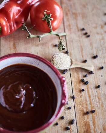 Foto von einem Schälchen mit BBQ Sauce mit Whiskey und Heidelbeeren. Auf dem Foto sind auch Paprika und eine Tomate zu sehen. | © SONNENTOR