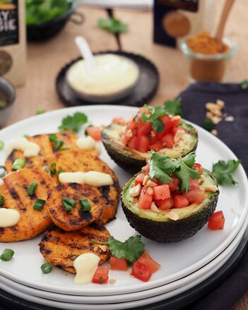 Auf dem Foto sieht man Süßkartoffelscheiben. Daneben sieht man eine gefüllte Avocado. | © SONNENTOR