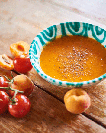 Auf dem Foto sieht man eine Schale mit Tomaten-Marillen Suppe. Daneben sieht man frische Tomaten und Marillen. | © SONNENTOR