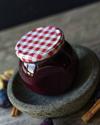 Auf dem Foto sieht man ein Glas mit Zimt-Marmelade. Daneben liegen Zwetschken und Zimtstangen. | © SONNENTOR