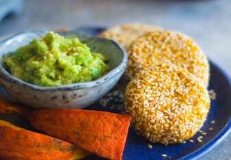 Auf dem Foto sind gebackene Kürbisfalafel, Avocadodip und Süßkartoffeln auf einem blauen Teller angerichtet zu sehen.  | © SONNENTOR