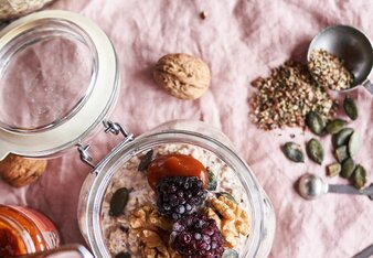 Auf dem Foto ist ein Glas Power-Porridge zu sehen. Daneben liegen Walnüsse, Kürbiskerne und Gewürze. | © SONNENTOR