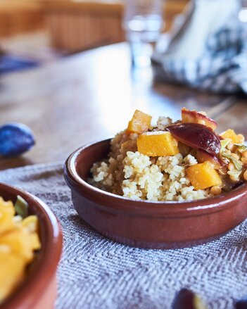 Auf dem Foto ist eine Form mit Tajine mit Kürbis und Zwetschken zu sehen. Die Form steht auf einem blauen Tuch. | © SONNENTOR