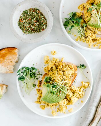 Auf dem Foto sieht man eine Scheibe Brot mit Veganer Eierspeis darauf. Auch Avocado und Sprossen sind auf dem Teller zu sehen. | © SONNENTOR