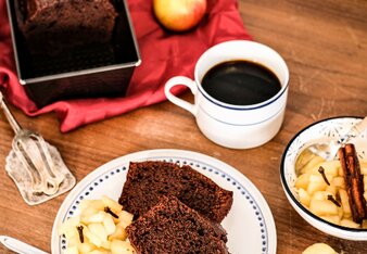 Auf dem Foto sind zwei Stück Schokoladen-Mandelkuchen zu sehen. Daneben sieht man Apfelkompott mit Nelken. | © SONNENTOR