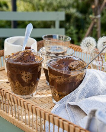 Auf dem Foto ist in eine Glas Löwenzahnwurzel-Stracciatella-Eis zu sehen. Darauf ist Schokoladensauce zu sehen. | © SONNENTOR