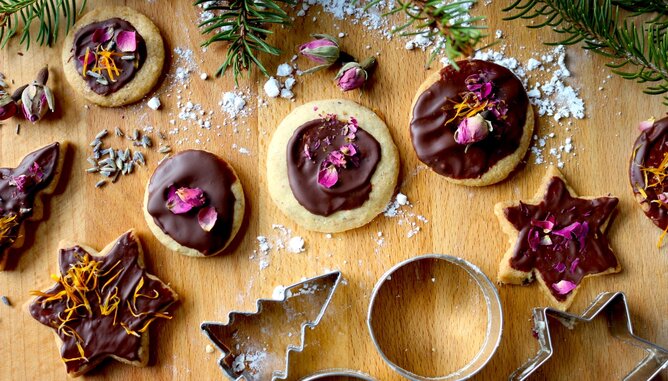 Auf dem Foto sind weihnachtliche Kekse mit Schokoglasur und Blüten zu sehen. | © SONNENTOR