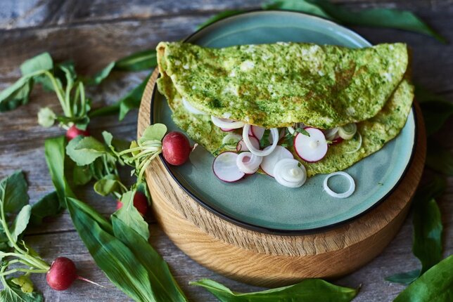 Auf dem Foto ist ein grünes Wildkräuteromelette zu sehen. Es ist mit Radieschen und Zwiebeln gefüllt. | © SONNENTOR