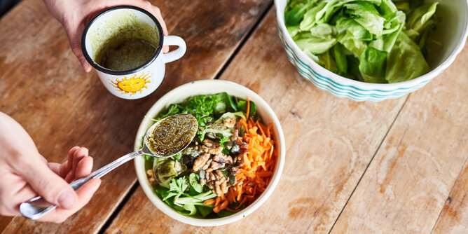 Auf dem Foto sieht man eine Schale mit buntem Salat und Superfoods darin. Man sieht wie jemand ein Dressing darüber gießt. | © SONNENTOR