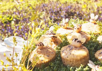 Auf dem Foto sind Muffins im Kräuterbeet zu sehen. Diese sind mit Marzipan-Bienen dekoriert. | © SONNENTOR