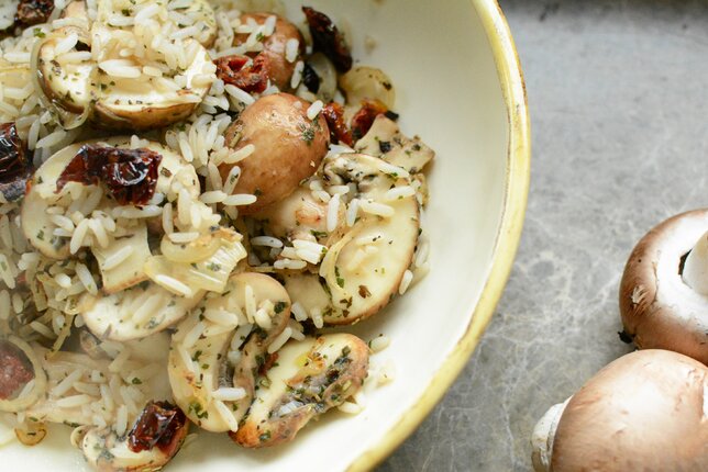 Auf dem Foto ist ein Teller mit Reispfanne zu sehen. Daneben liegen frische Champignons. | © SONNENTOR